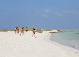 Grupa turystów spacerujących po plaży na jednej z wysp Qulaan w Marsa Alam