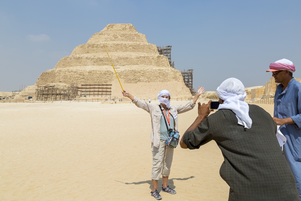 Turysta fotografuje się na tle piramidy schodkowej w Sakkarze