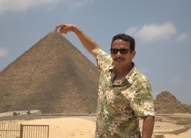 Mężczyzna dotyka palcem wierzchołka Wielkiej Piramidy w Gizie